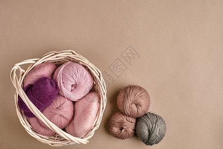 毛线球和织针用于在米色背景的柳条碗中编织的彩色纱线针织作为一种针线活五颜六色的图片