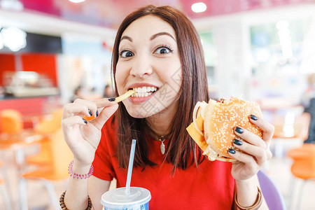 快乐的年轻女子在快餐厅吃汉堡包苏背景图片