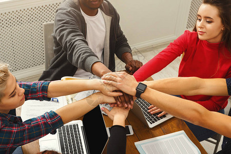 年轻的多元化商界人士在工作桌背景下双手合十成功的创业团队团图片