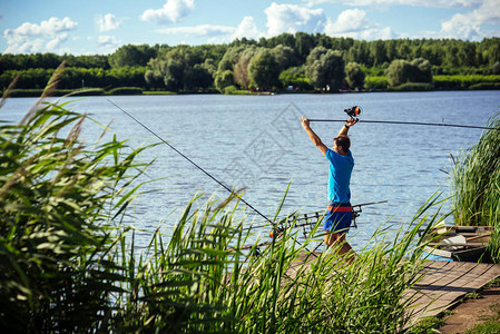 在木码头上用旋转滑车钓鱼的人渔夫在湖水或河水中投钓竿冒险运动活动旋转钓鱼图片