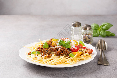 美味的意大利面条盘装满了碎牛肉粉红干酪奶樱桃西红柿和新鲜烤背景图片