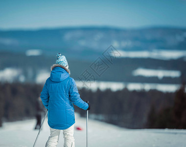 蓝夹克和羊毛帽的女滑雪者站在滑雪图片