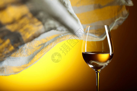 黄色背景的白葡萄酒杯子黄色织物在风中飘背景图片