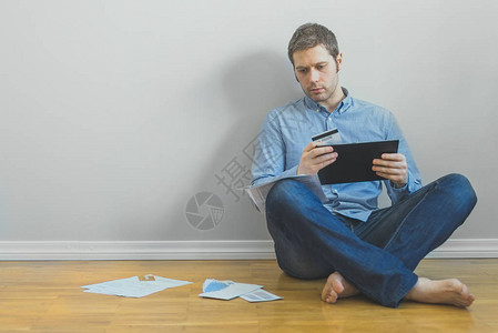 英俊的男人使用平板电脑和信用卡支付账单图片