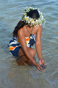 年轻有吸引力和异国情调的波利尼西亚库克岛民妇女在库克群岛拉罗汤加的穆里泻湖的黑唇牡蛎壳中拿着大溪地黑珍珠真实的图片