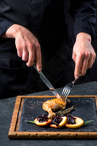 独家餐厅点黑盘子上的美味鸭腿准备好的鸭腿背图片