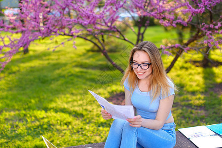 漂亮的女学生在春季开阔的公园学习论文图片