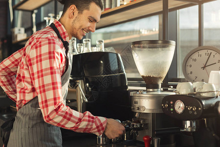 快乐的酒保用现代咖啡机制作浓缩咖啡准备支撑饮料的人小企业和专业图片