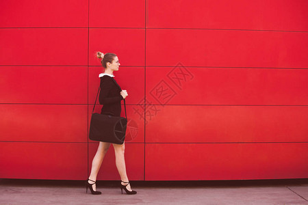 年轻优雅的女商人在市里走在红墙图片