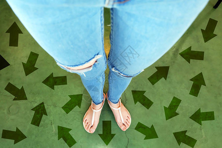不同方向的未来箭头站在绿色箭头线选择的女人上方的自拍照城市背景下街道路上的鞋子女人背景图片