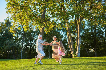 有祖父母在户外跳舞的女孩在绿草上长圆环一代背景图片