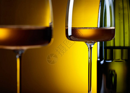 黄色背景的白葡萄酒玻璃和瓶子图片