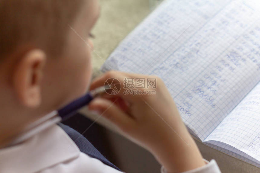 家庭教育男孩手用笔在传统的白色记事本纸上手写英文单词男孩给朋友写了一封信放学图片