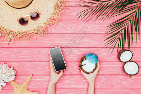 妇女用智能手机和椰子鸡尾酒在粉图片