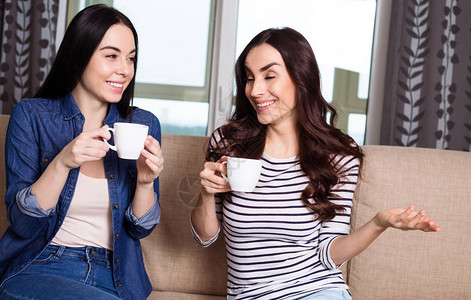 两个微笑着的美女在家里喝咖啡或茶图片