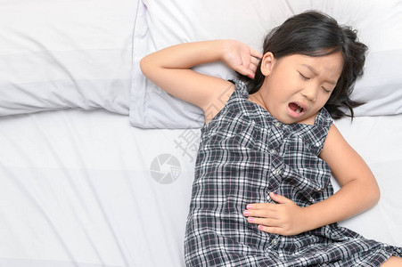 患有胃痛和躺在床上的亚洲儿童背景图片