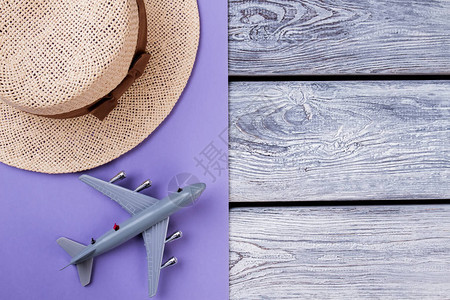草帽和玩具飞机木质和紫色背景旅行图片