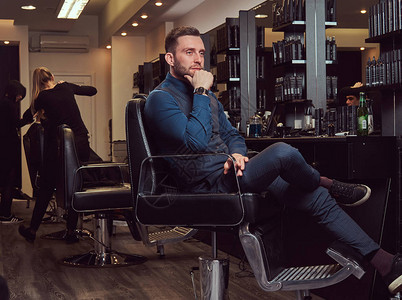 一个专业理发师坐在理发椅上等着下一图片