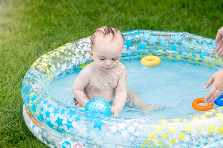 男孩婴儿坐在充气游泳池里玩图片