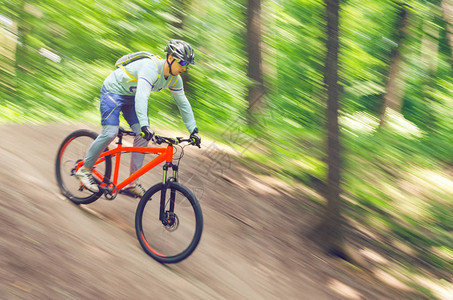 一个戴头盔的骑自行车的人从山上下来骑着橙色自行图片