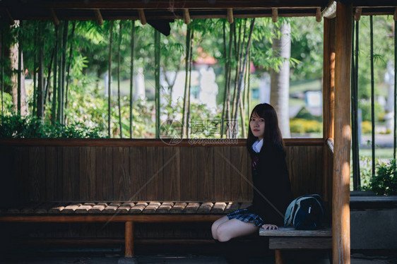 坐在日本花园和竹林的日本女学生肖像般年轻的图片