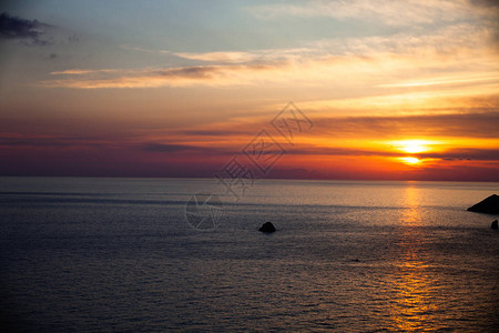 在海滩的日落与云彩平静的海水天空中美丽的色彩蓝色和橙色调安静的地方海滩放松的场景背景图片