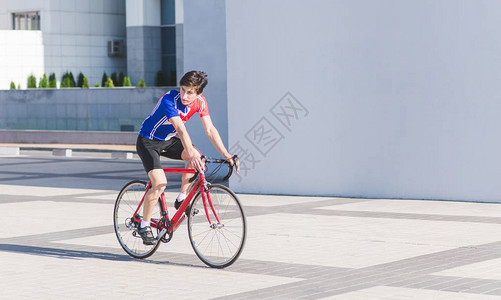 服骑单车的骑手在建筑背景上骑一辆红色公路自行车背景图片