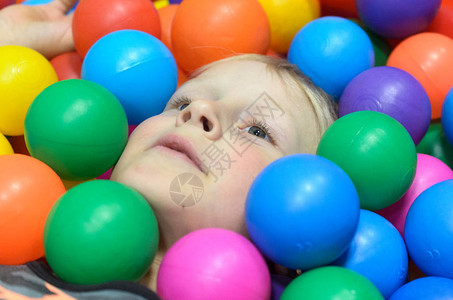 男孩躺着埋在游戏室的彩球里图片