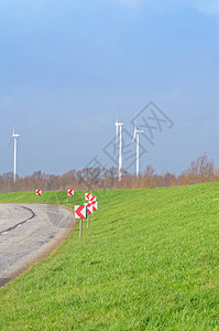 乡村公路绿色草地和三台风力涡轮机对抗蓝色多云的天空图片