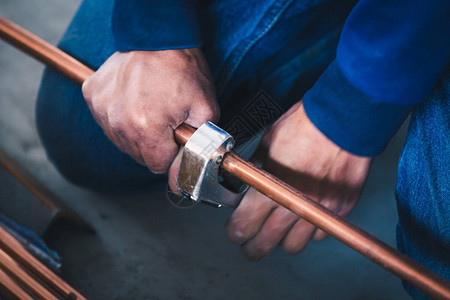工业系统男工人与铜管空调工具联合切图片