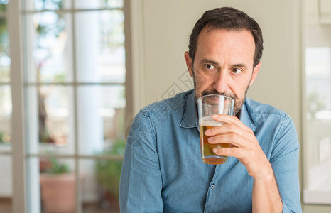 中年男子喝酒啤酒自信地表现在聪明的面图片