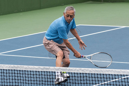 健康的老人在接近低网球背手排时表现出灵活笑声背景图片