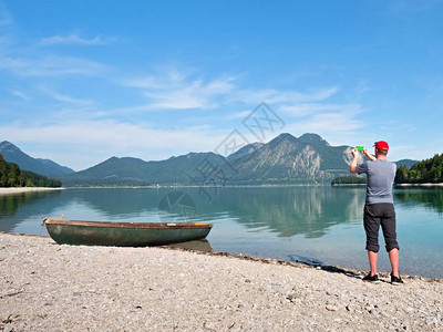 摄影师目视观光员正在拍摄与阿尔卑斯山为背景的湖照片图片