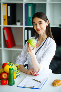健康光室里幸运营养师的画像持有青苹果和厘米丝带健康的营养新鲜蔬菜和图片