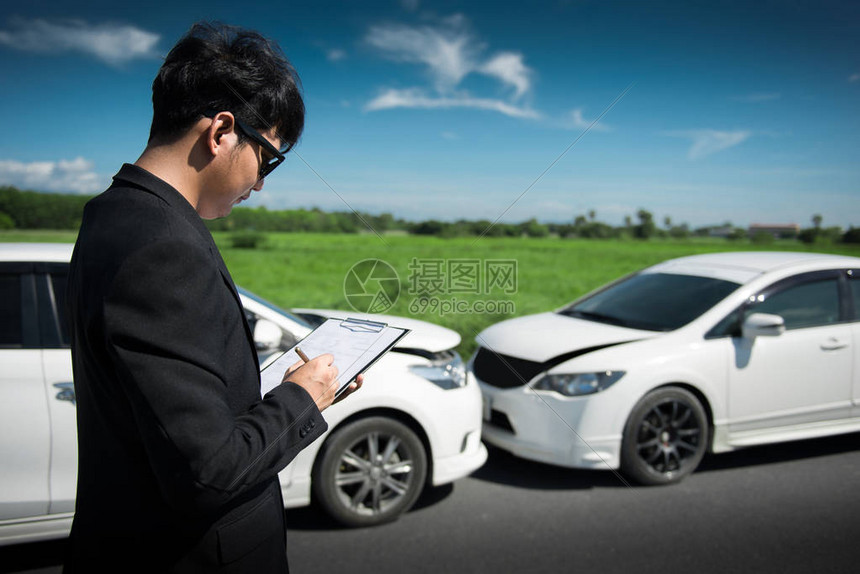 保险代理人员在事故后检查车辆时在剪贴板上写作的侧面视图图片