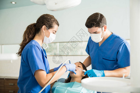 男牙医和女牙医在诊所用牙科工具检图片