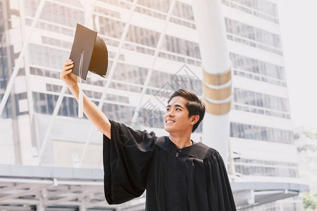 欢庆学生在校园建筑背景上庆祝成功毕业图片