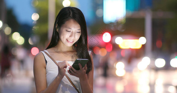 女人晚上在城市玩手机图片