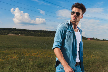 身穿牛仔衬衫和太阳镜的青年临时男子站在草地上图片