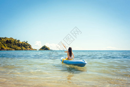 女人在海上的一条皮艇上漂泊在清澈的背景图片