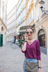 快乐的女士通过智能手机在European街上聊天维也纳市有吸引力的年轻旅图片
