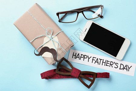 彩色背景上装有礼品箱智能手机和男饰物的装饰品父亲节背景图片