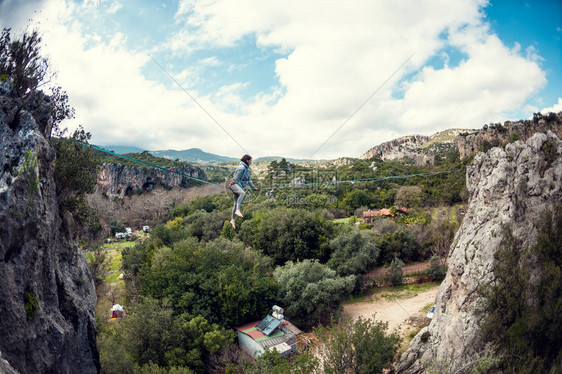一个女人在线上保持平衡在高空吊索通过的能运动员在大自然中锻炼危险和保险那个女孩坐在线图片