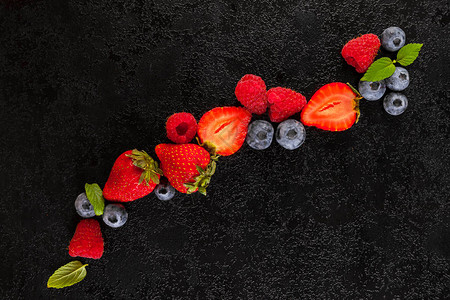 黑桌上的草莓蓝莓和青莓图片