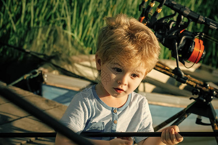 带着惊讶的脸在河上钓鱼的小孩钓鱼码头上拿着鱼竿的男孩暑假图片