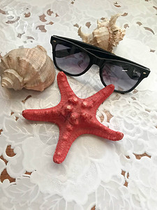 美丽的红海星和黑太阳镜被装饰在白布底的贝壳上海洋热带夏季背景笑声图片