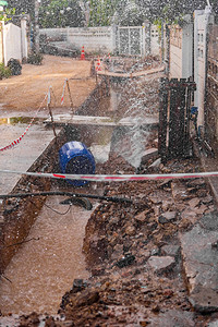自来水水管自来水喷泉的图像从管道中渗出在简陋的街道建设和固定地面下室背景