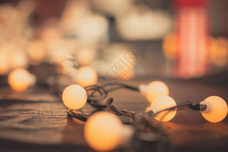 羊毛和模糊背景的选择焦点装饰灯和闪亮的楣布上的灯泡暖光圣诞节背景晚上聚会的图片