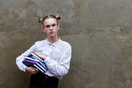 高中大学重读的年轻女孩持有书籍灰色混凝土墙底背图片