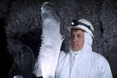 洞穴中的气候学家在冰晶覆盖的黑岩背景下背景图片